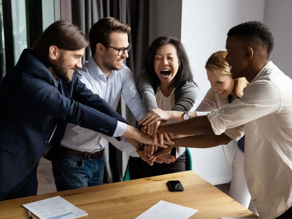 Colleagues joining hands over a table